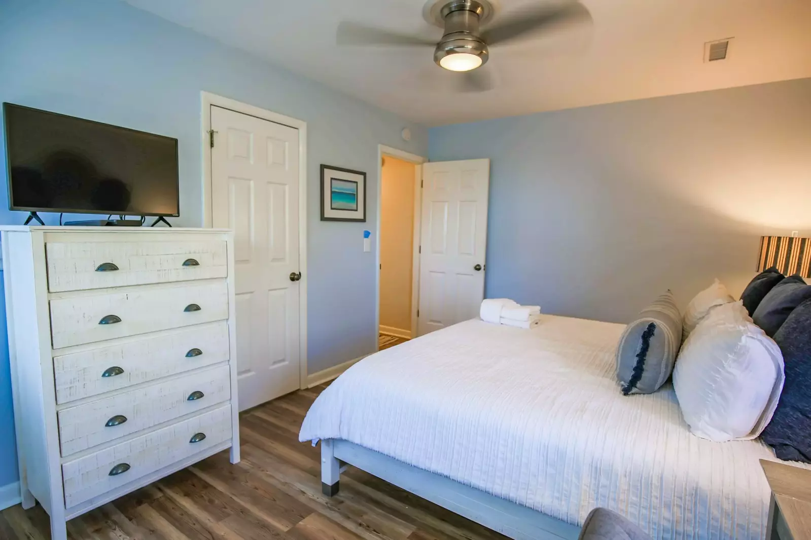 The bedroom also has a ceiling fan, dresser and TV.