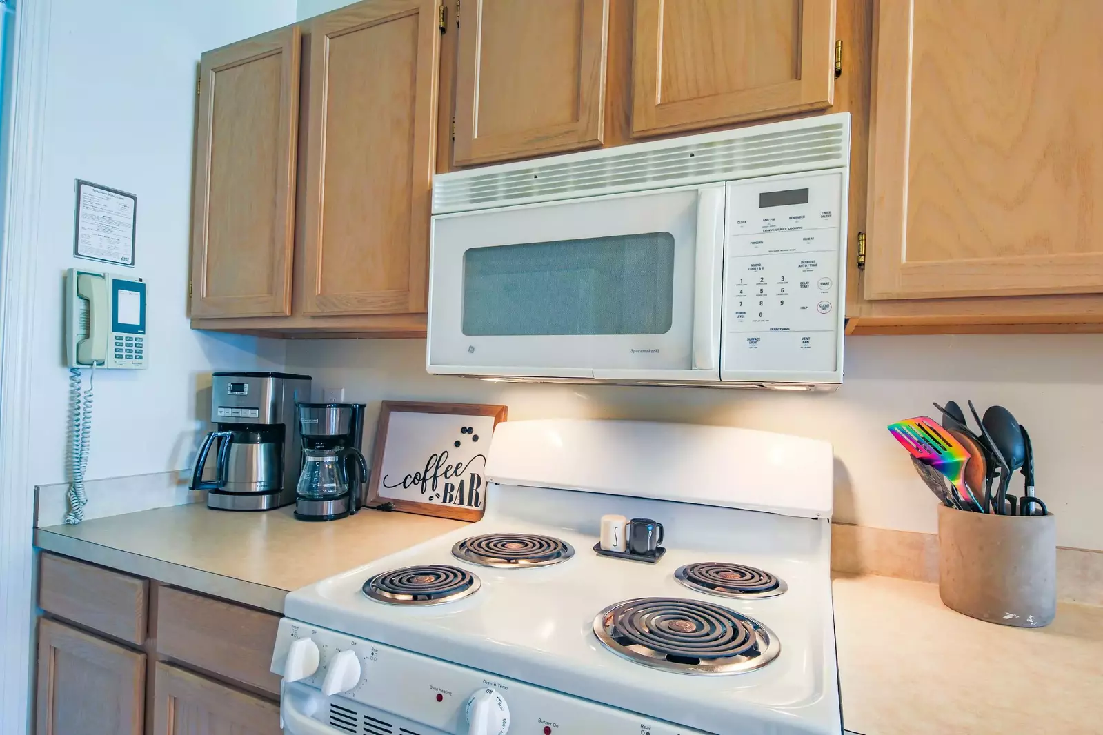 The kitchen features white appliances, including an electric range and microwave.