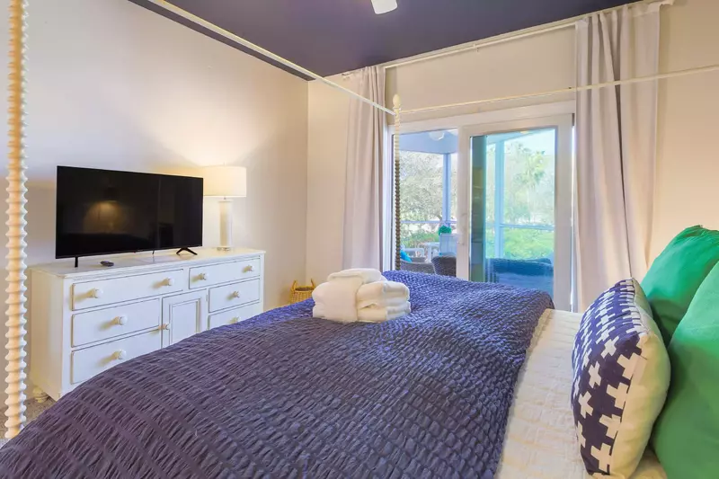 The master suite features a king bed, dresser with smart TV and access to the screened porch.