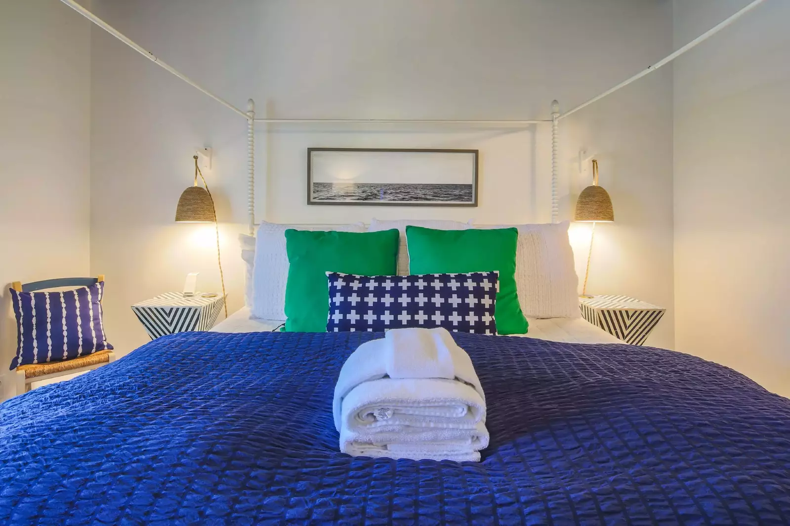The master suite also features night stands with wall sconces and a chair.