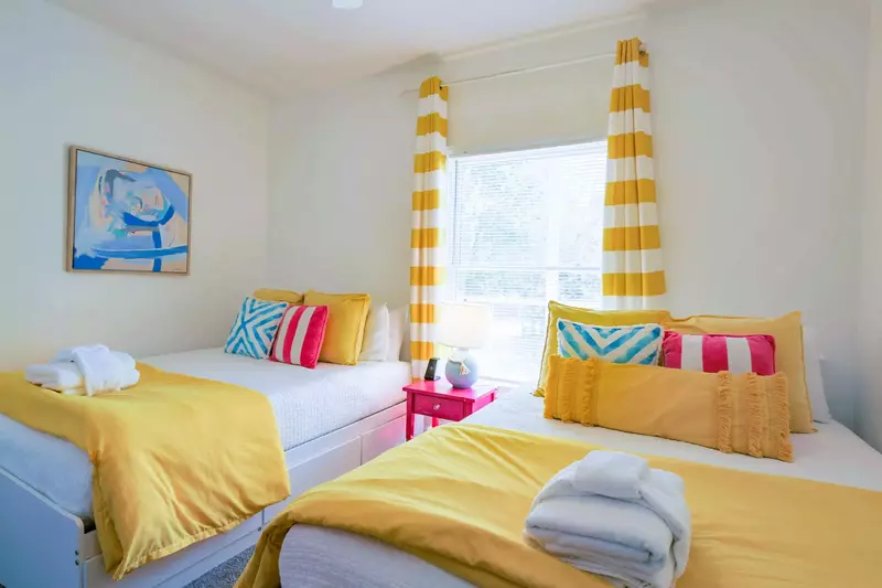 The guest bedroom features two queen beds and a night stand with a reading lamp.