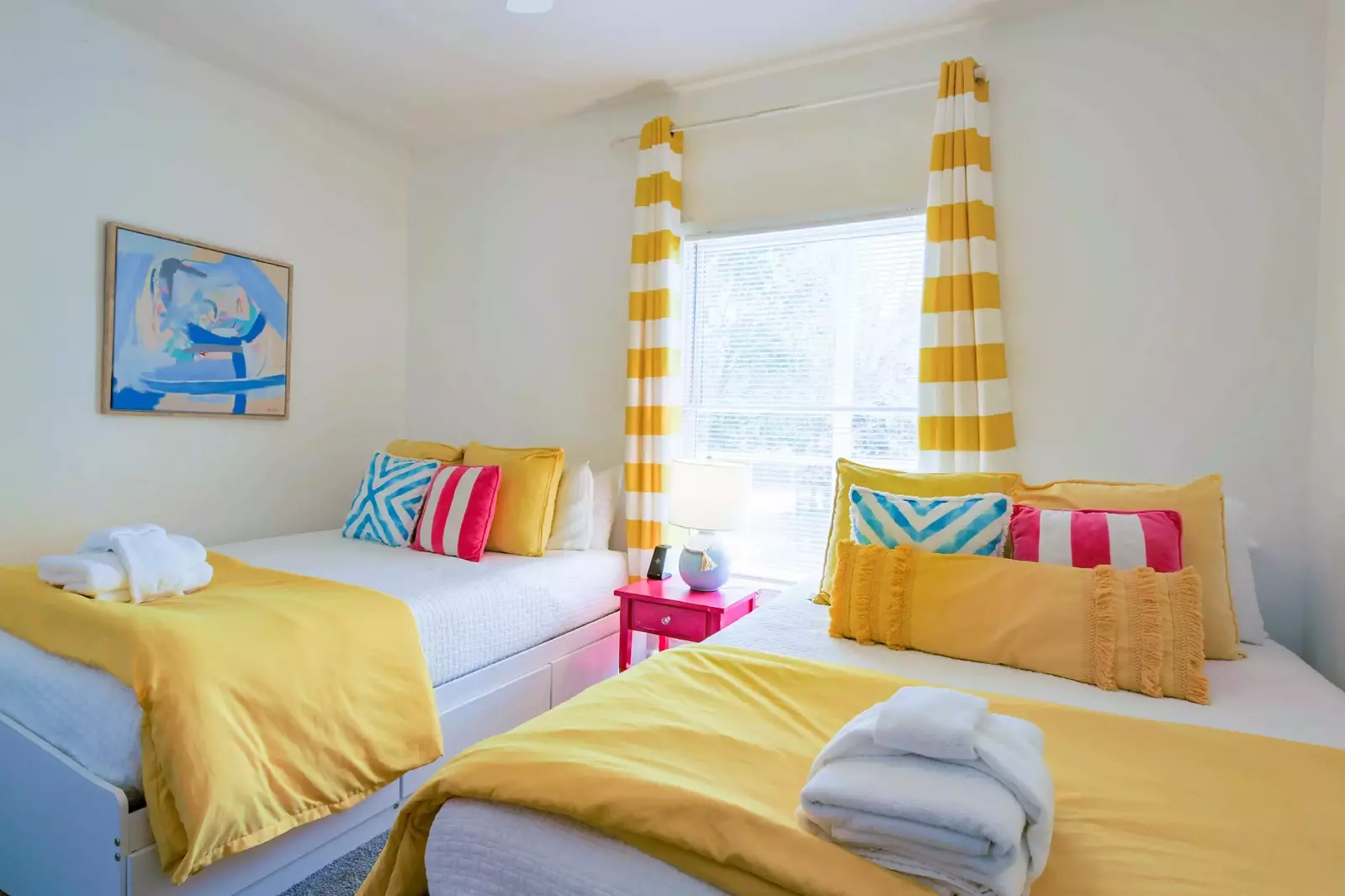 The guest bedroom features two queen beds and a night stand with a reading lamp.