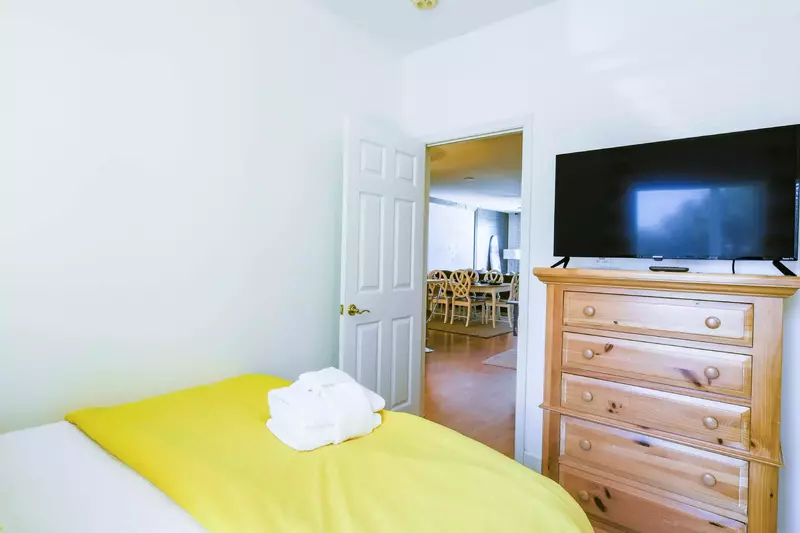 The guest bedroom also features a dresser and TV.