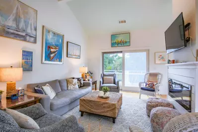 The living room features vaulted ceilings, spacious seating, a wall-mounted streaming TV and access to the back porch.