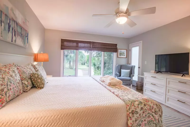 The master suite also has a dresser with smart TV, a ceiling fan, arm chair and golf course views.