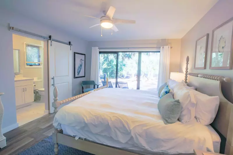 The master suite also has a mounted smart TV, a ceiling fan, full length mirror and a dresser.