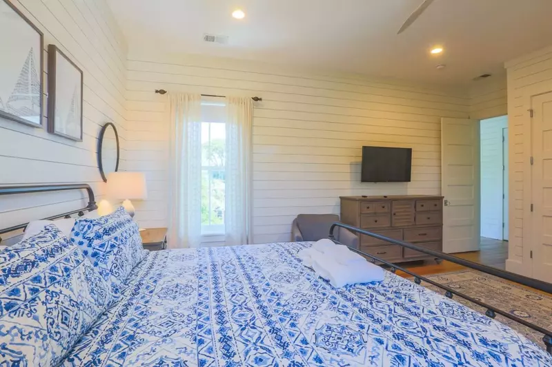 The master bedroom has a dresser and mounted smart TV.