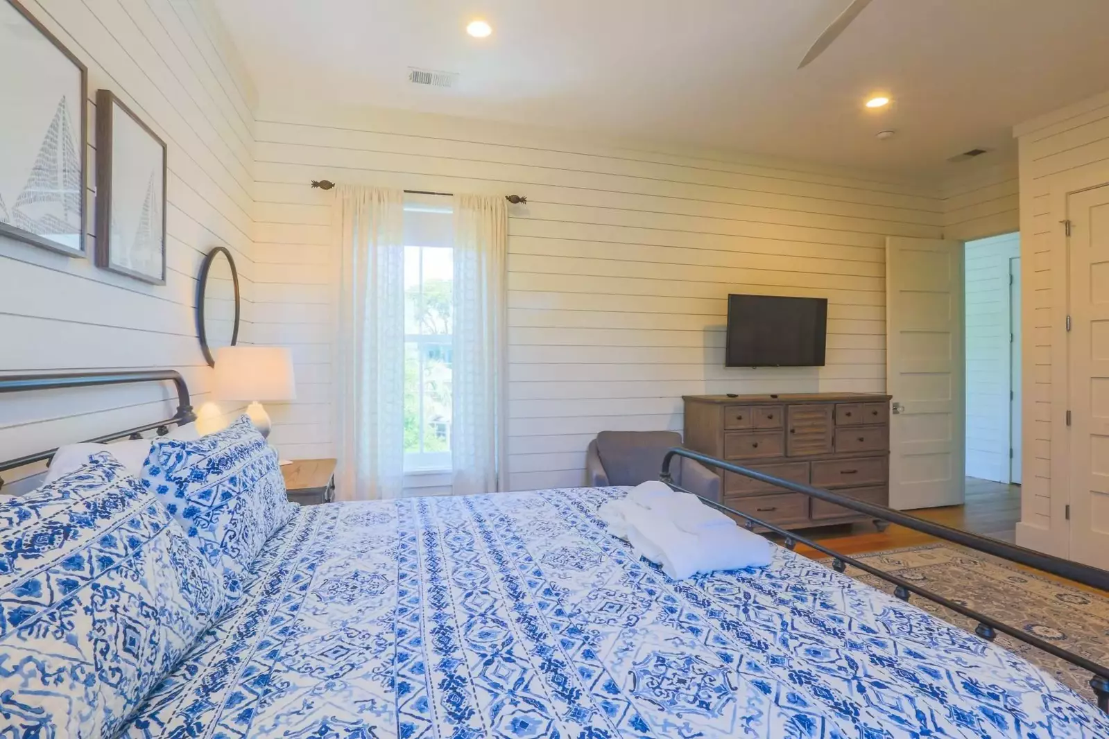 The master bedroom has a dresser and mounted smart TV.