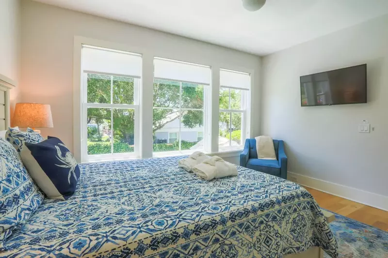 The bedroom has a mounted smart TV and wonderful natural light.