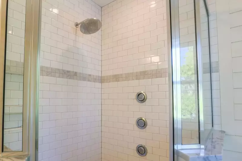 The tiled walk-in shower has a rain showerhead and three body sprays.