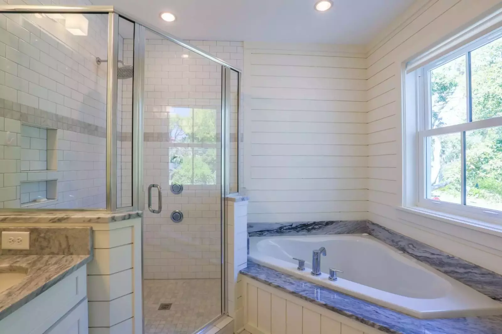 The en suite bath for the first floor master suite features a soaking tub and tiled walk-in shower.