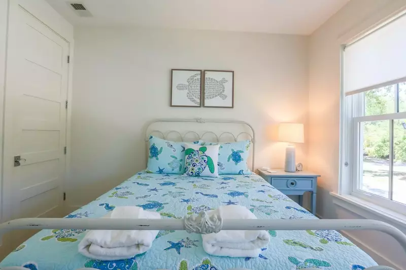 This bedroom has a queen bed and a night stand with a reading lamp.