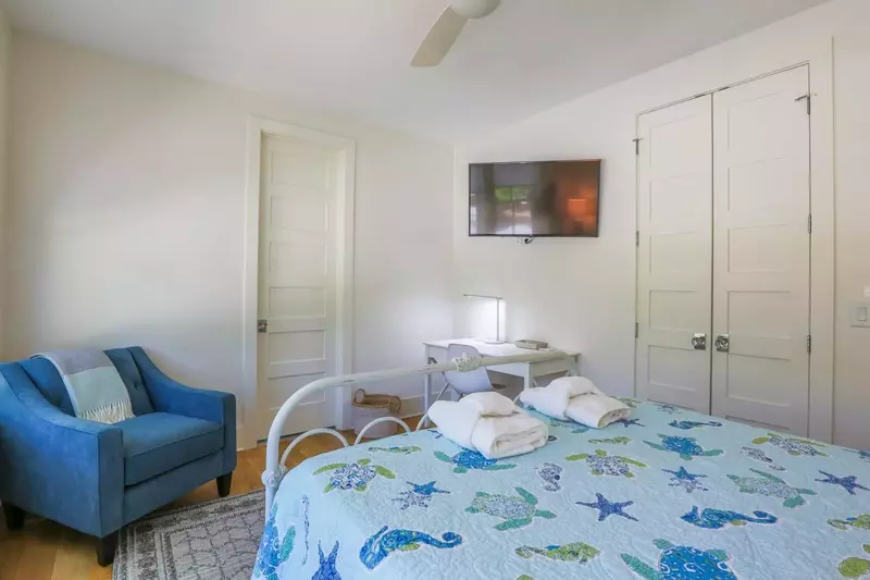 This guest bedroom has a desk, a mounted smart TV and an en suite bathroom.