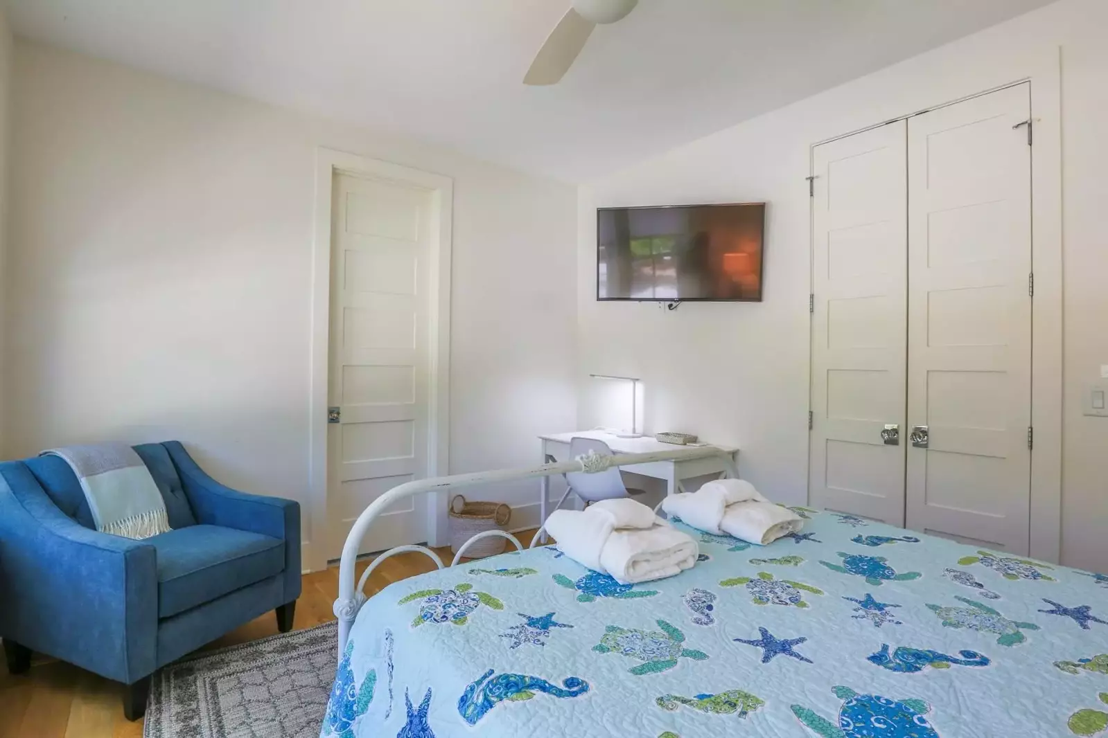 This guest bedroom has a desk, a mounted smart TV and an en suite bathroom.
