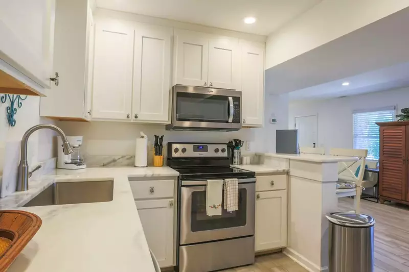 The kitchen features a range, microwave, basin sink and a drip coffee maker.