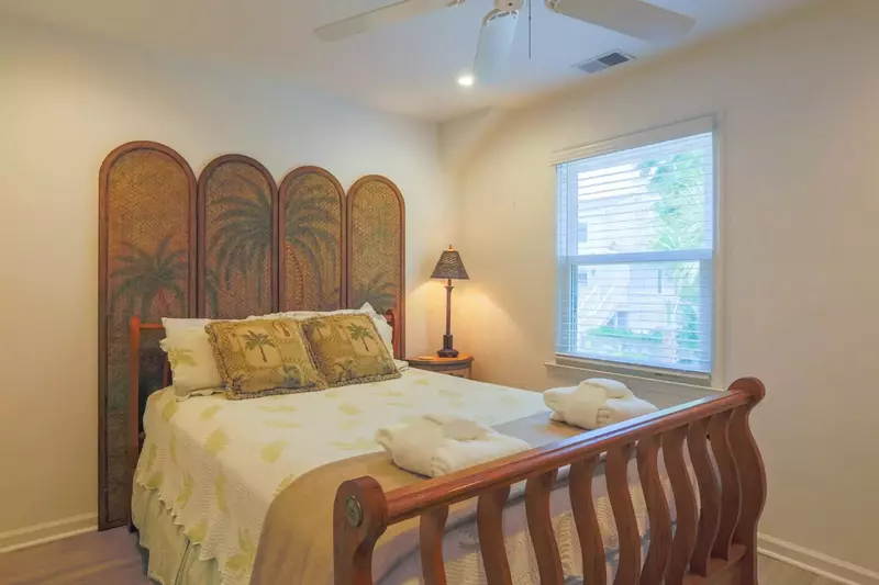 This bedroom features a queen bed, ceiling fan, nightstand with a reading lamp and a dresser.