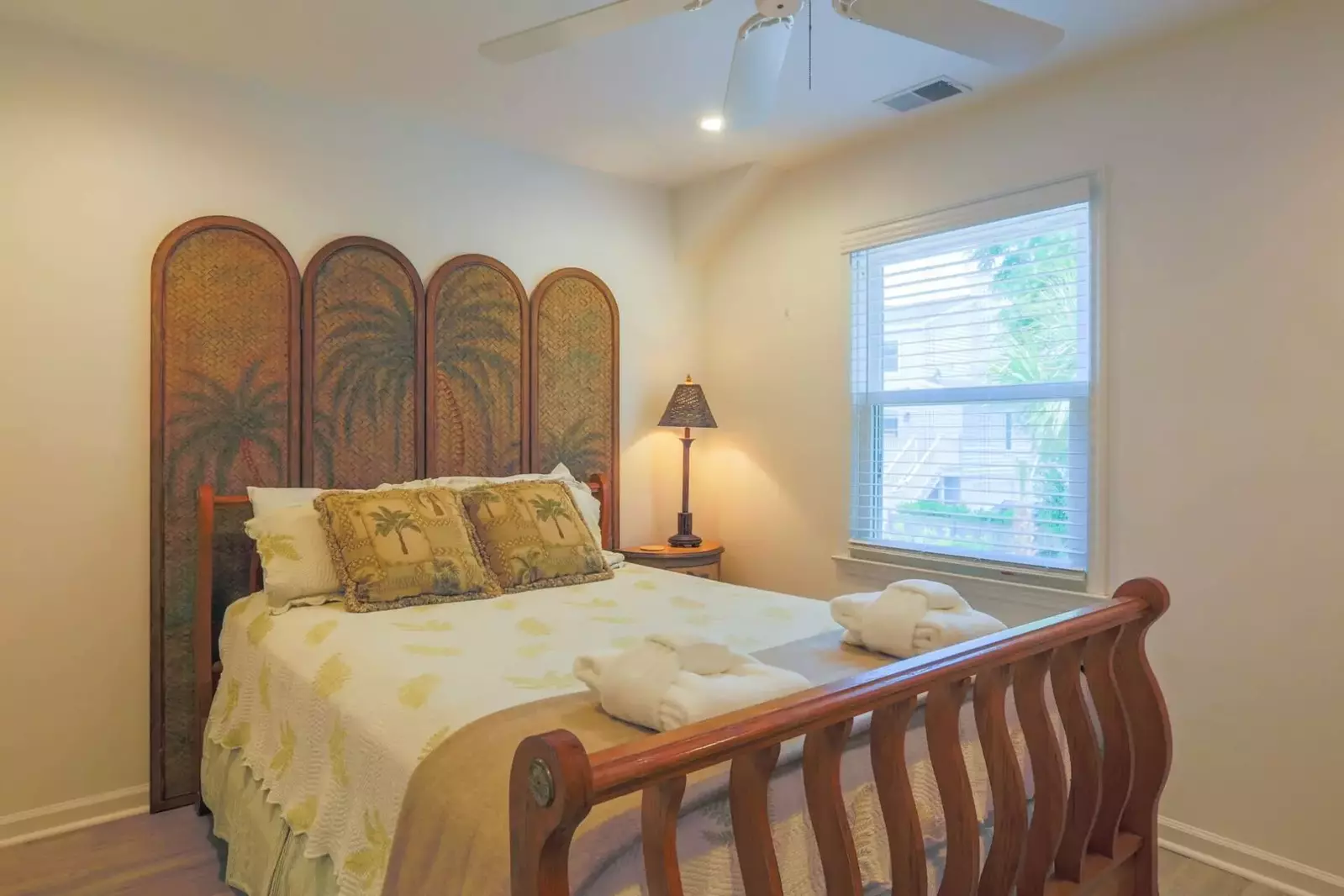 This bedroom features a queen bed, ceiling fan, nightstand with a reading lamp and a dresser.