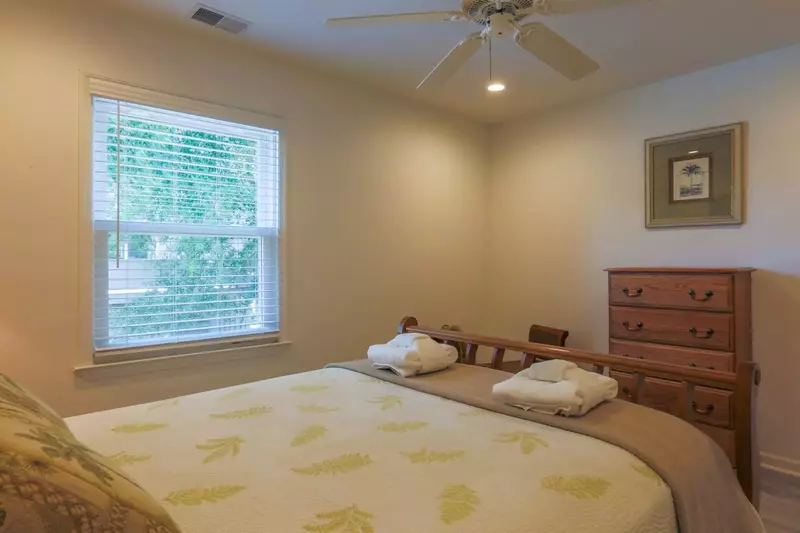 This second floor bedroom has a ceiling fan and dresser.