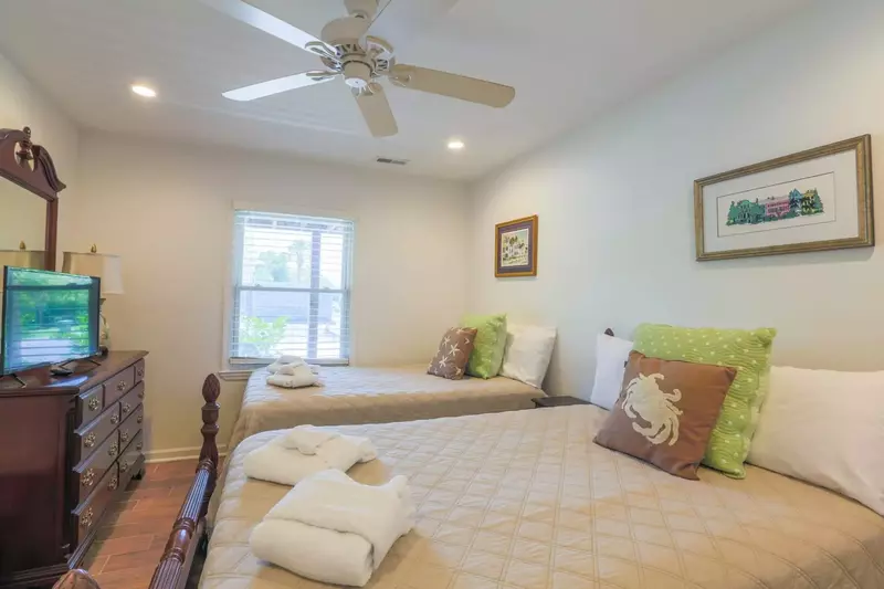 This first floor bedroom features two full beds, a dresser with a smart TV and nightstand.