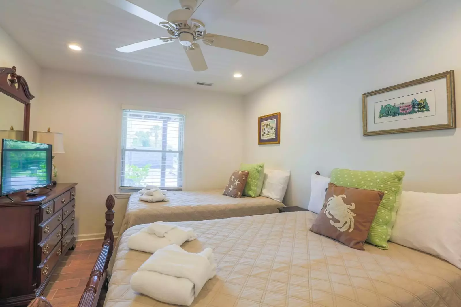 This first floor bedroom features two full beds, a dresser with a smart TV and nightstand.
