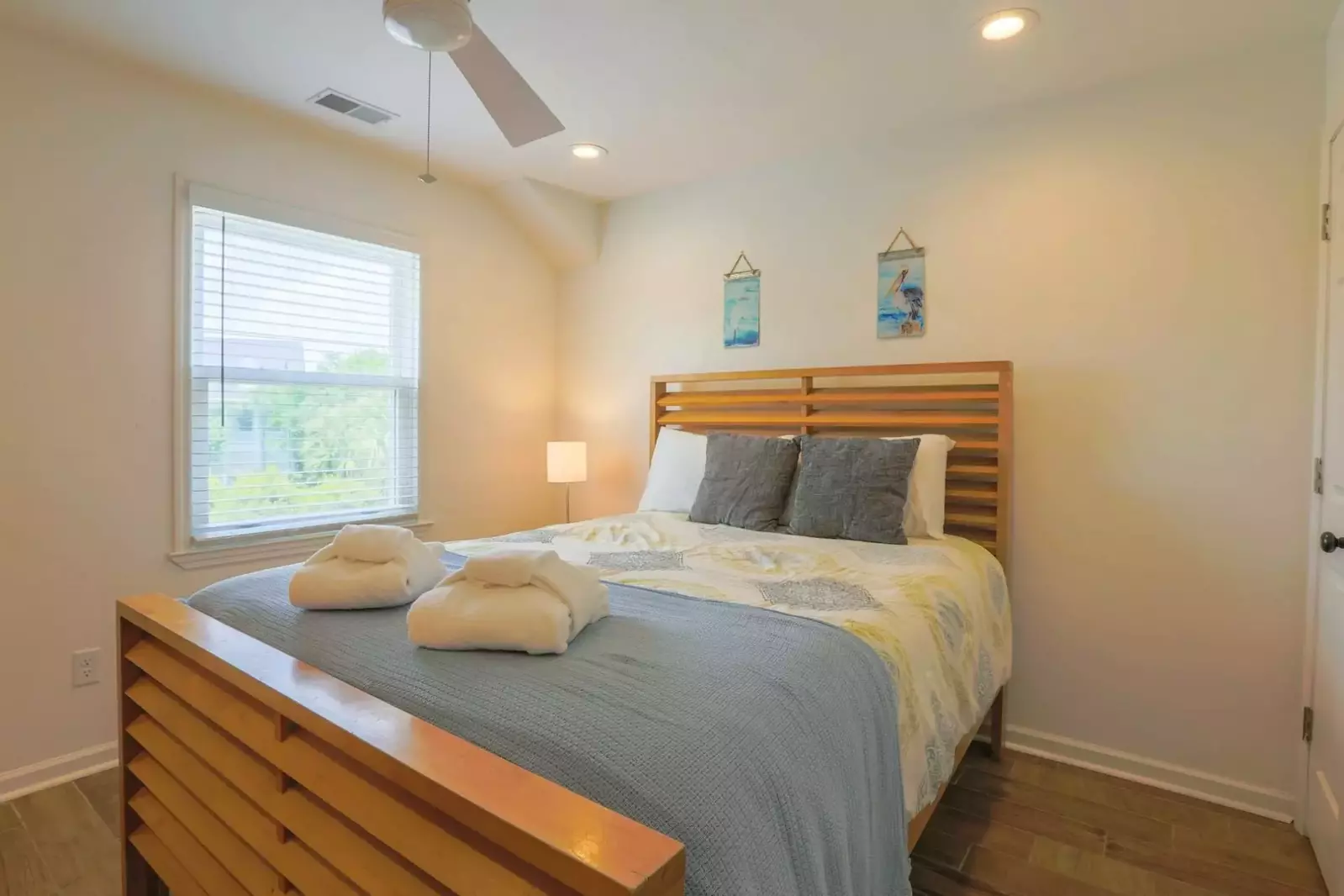 This guest bedroom features a queen bed, nightstand with reading lamp and a ceiling fan.