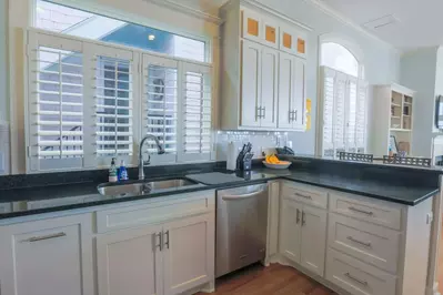 The kitchen for A Golden Sunrise features white cabinetry, a white tiled backsplash and stainless steel appliances.
