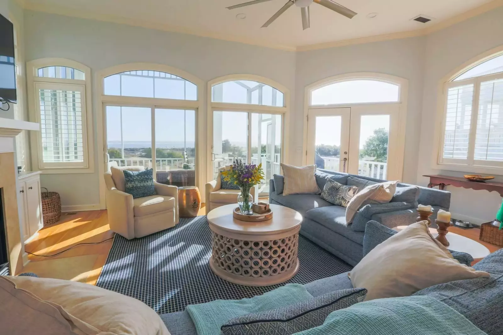 The living room has comfortable seating and arched windows looking out onto the beach.