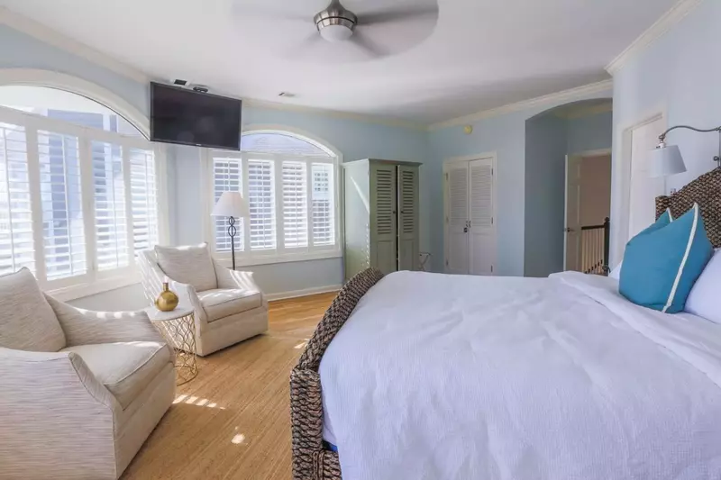The master bedroom has a seating area, mounted TV and ceiling fan.