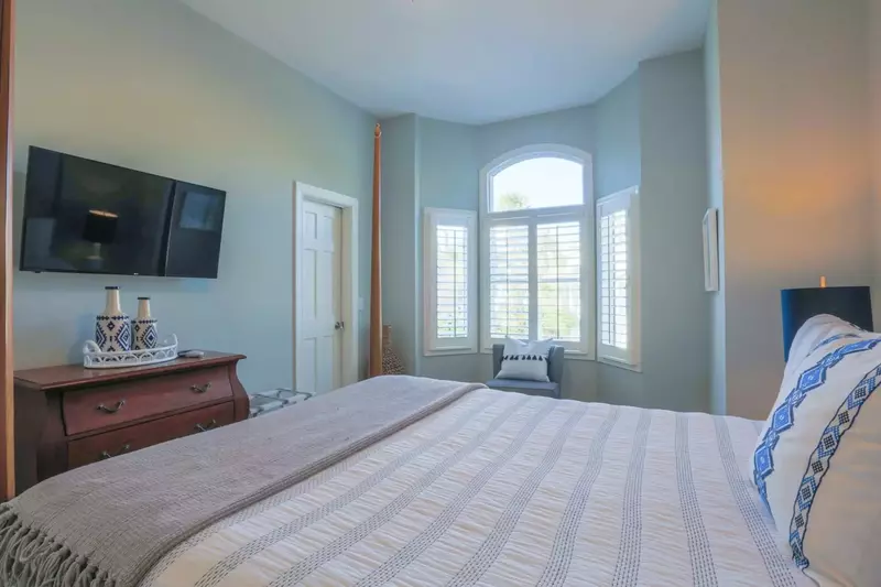 This guest bedroom also has a mounted TV and dresser.