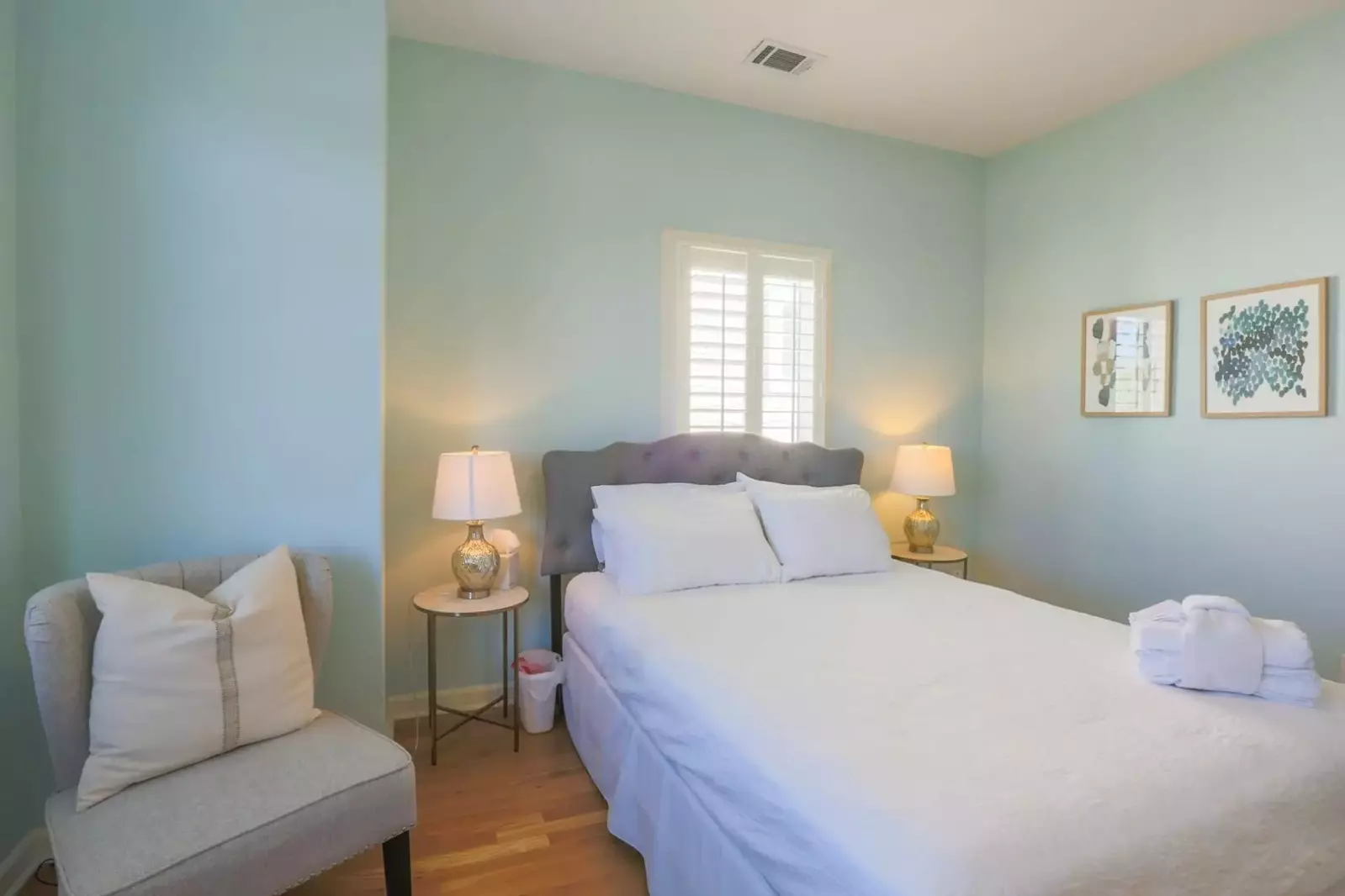 This guest bedroom features a queen bed, night stands with reading lamps and a chair.