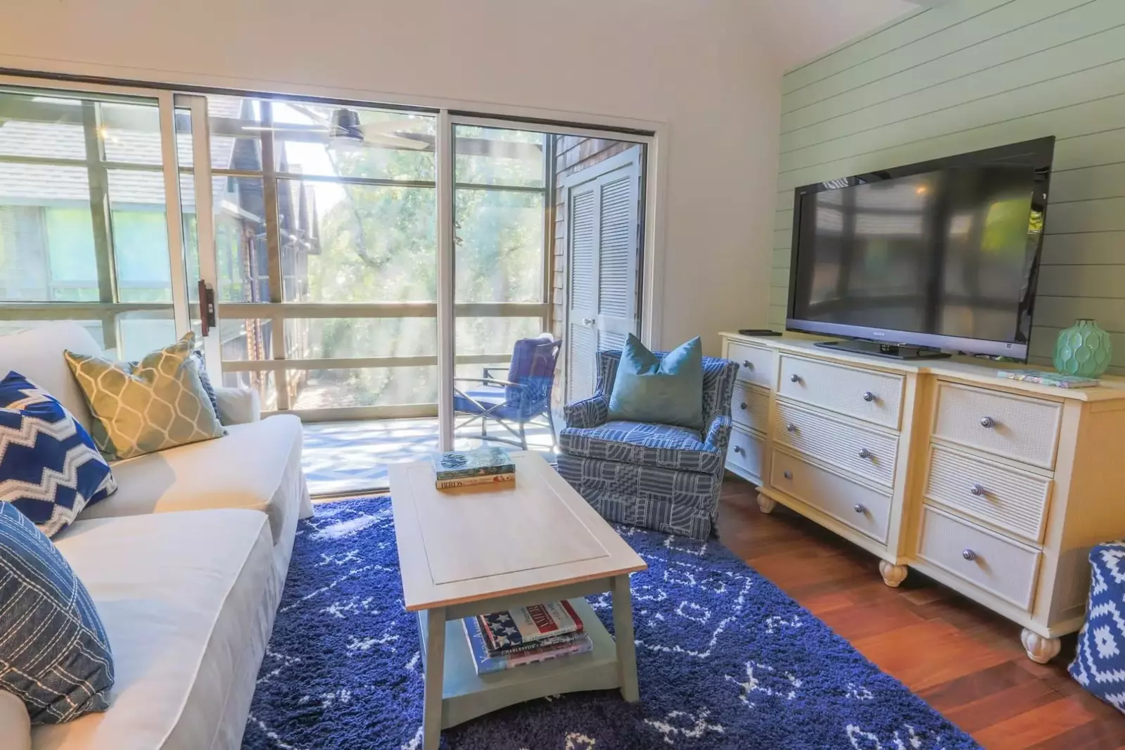 The living room connects to a spacious, screened porch via a large sliding glass door.