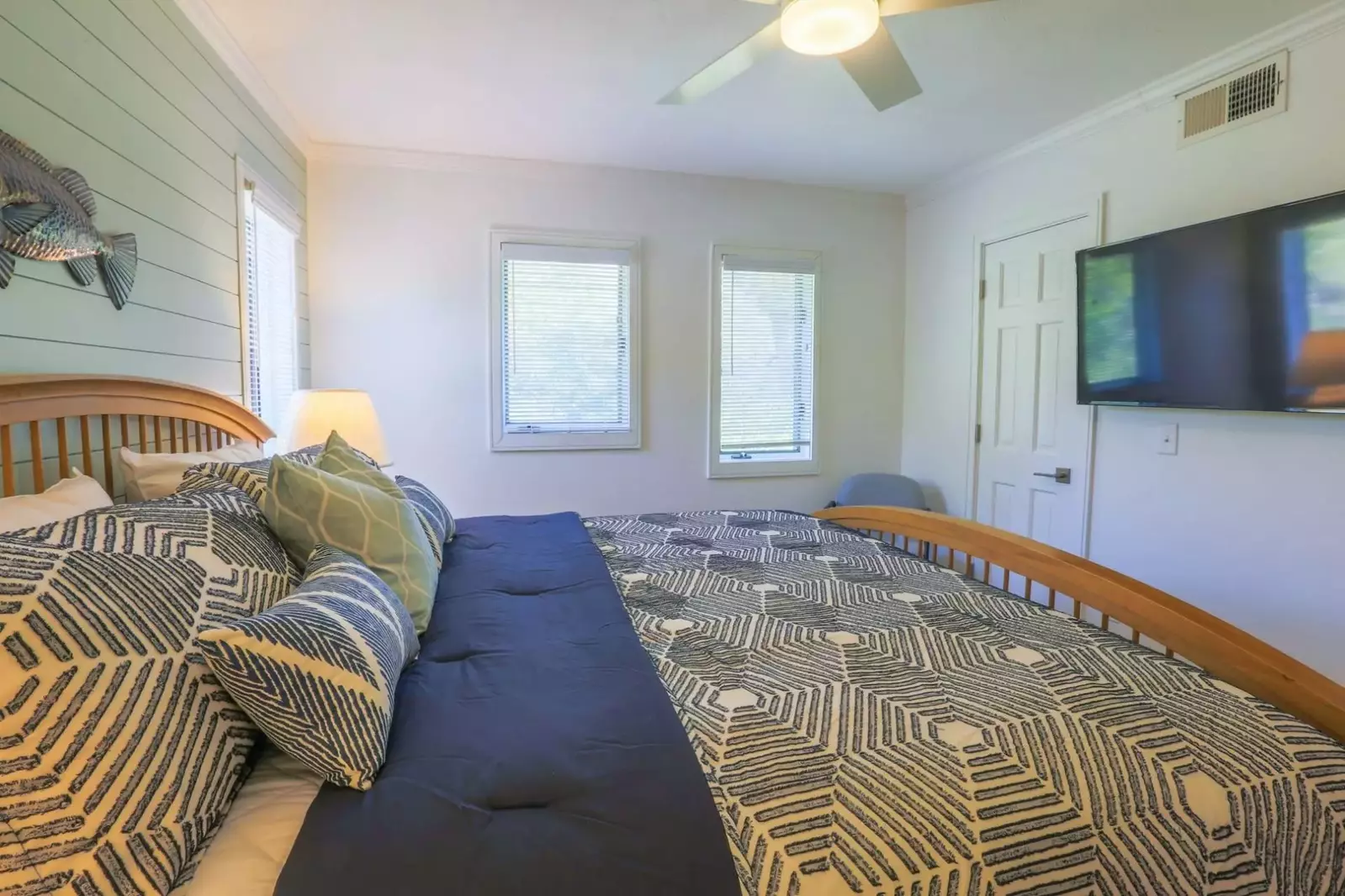 There is a mounted smart TV and ceiling fan in the bedroom.