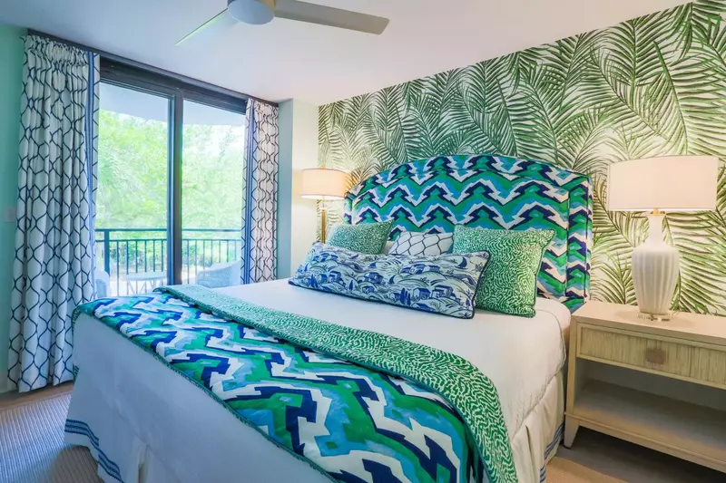 This guest bedroom features a king bed, nightstand, reading lamps and access to a private covered balcony.