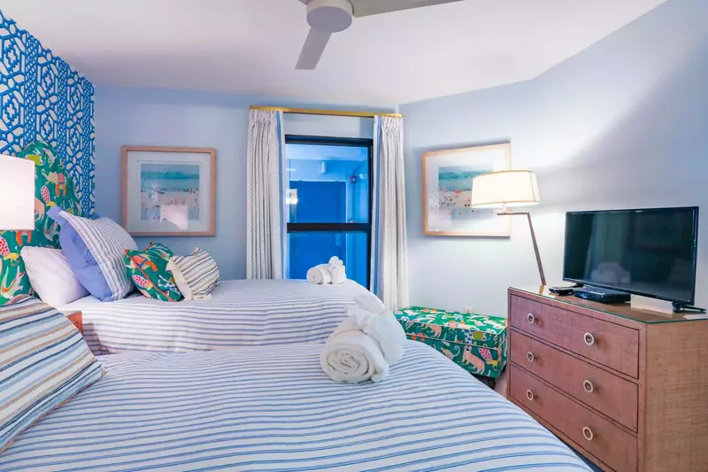 This bedroom also has a dresser, a TV, a bench and a ceiling fan.