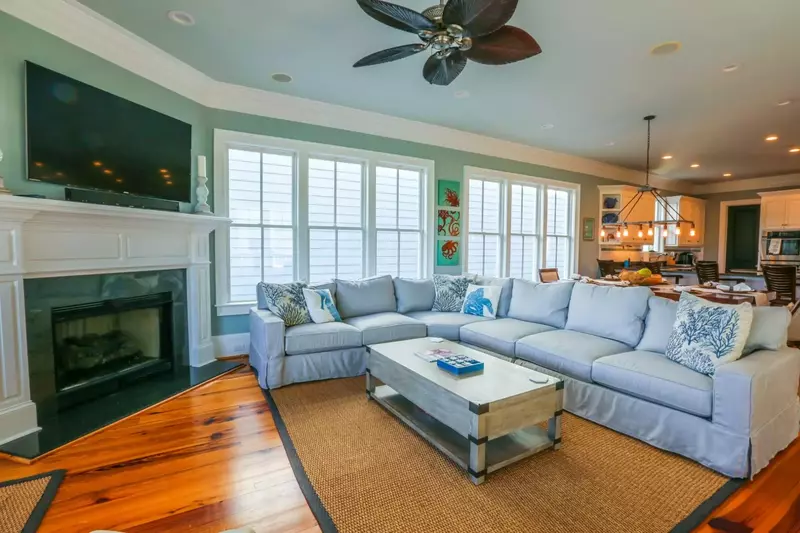 The living room features a large screen TV, spacious sectional, hardwood floors and ceiling fan.