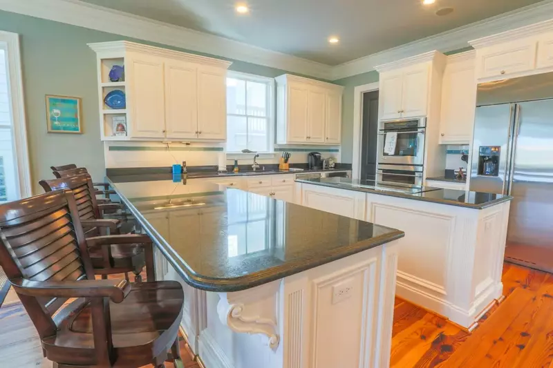 The expansive kitchen features white cabinetry, granite counters and stainless steel appliances.
