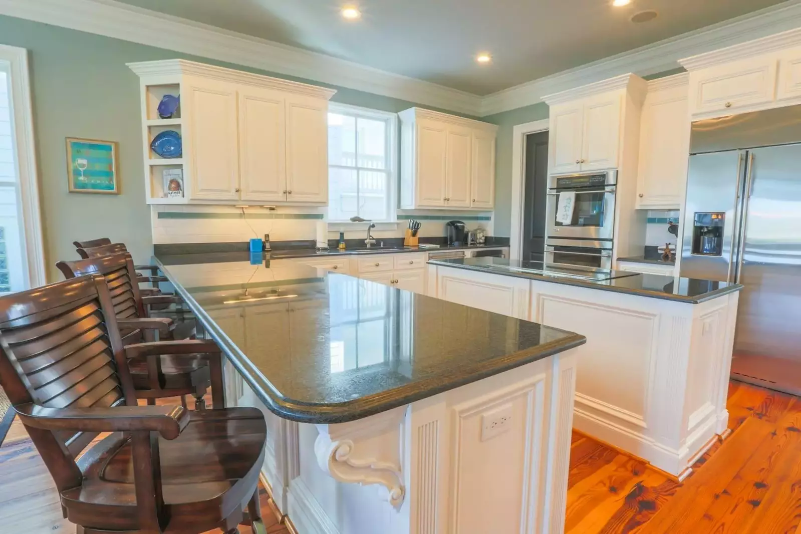 The expansive kitchen features white cabinetry, granite counters and stainless steel appliances.