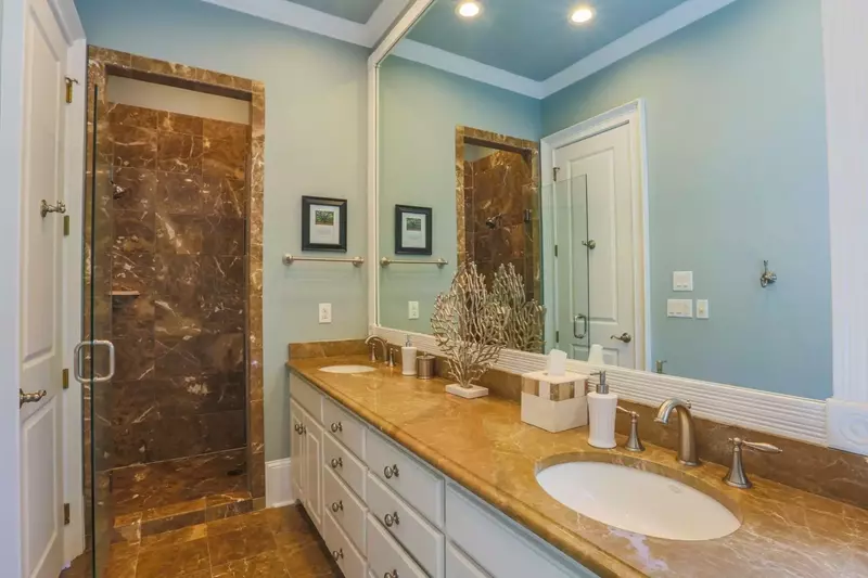 The en suite master bath is outfitted with a marble-topped vanity, marble floors and a marble & glass shower.