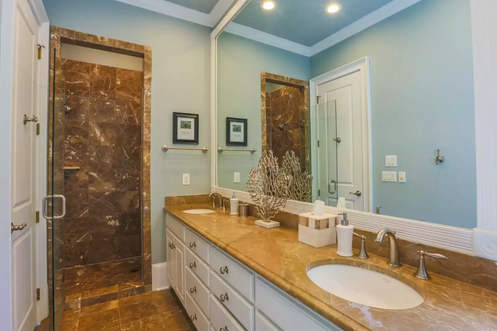 The en suite master bath is outfitted with a marble-topped vanity, marble floors and a marble & glass shower.