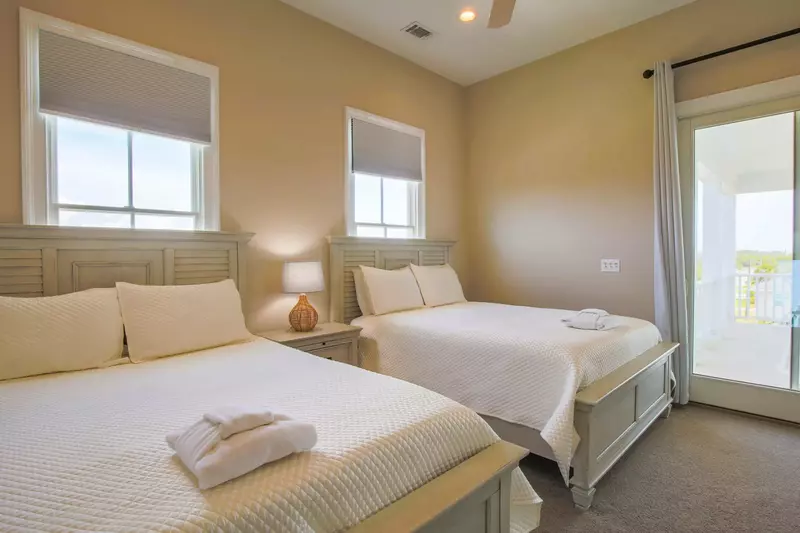 This room features two queen beds and sliding door access to the home's front porch.