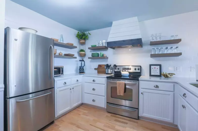 The kitchen has open shelving along the beautiful, white tiled walls.