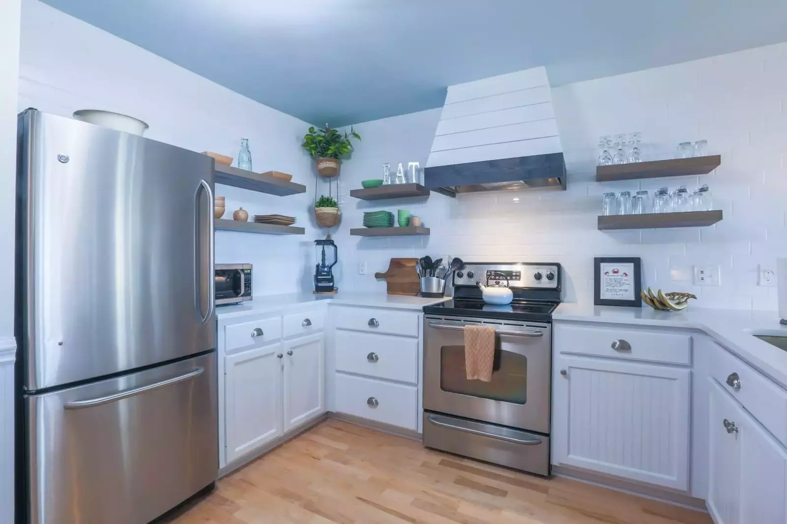 The kitchen has open shelving along the beautiful, white tiled walls.