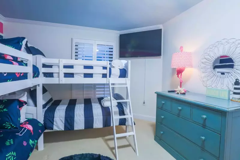 The bunk bedroom has a dresser and mounted smart TV.