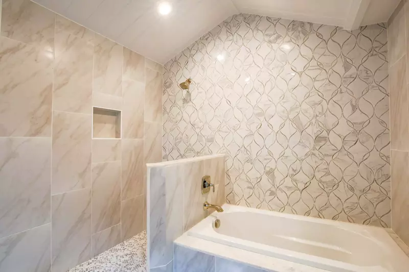 This tiled wall in the master suite bathroom is shared by the soaking tub and walk-in shower.