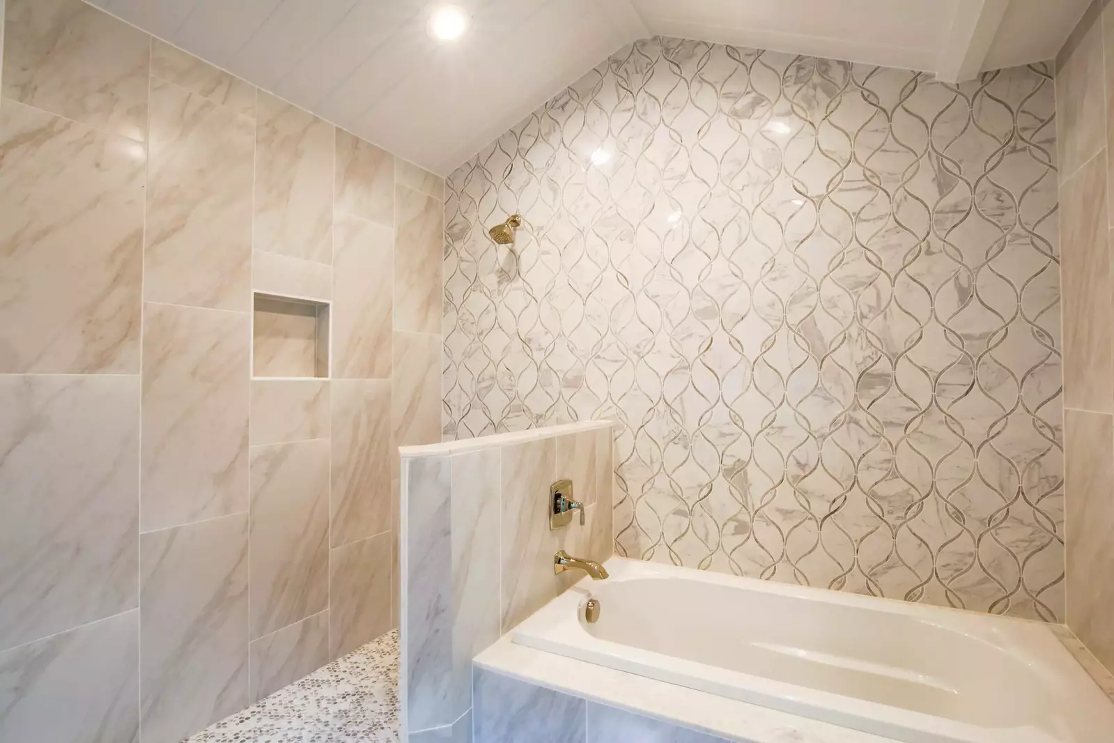 This tiled wall in the master suite bathroom is shared by the soaking tub and walk-in shower.