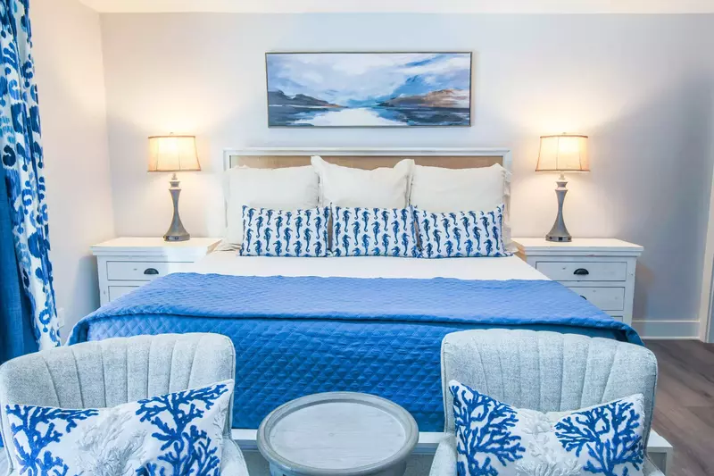This master suite features a king bed, night stands with reading lamps and a seating area.