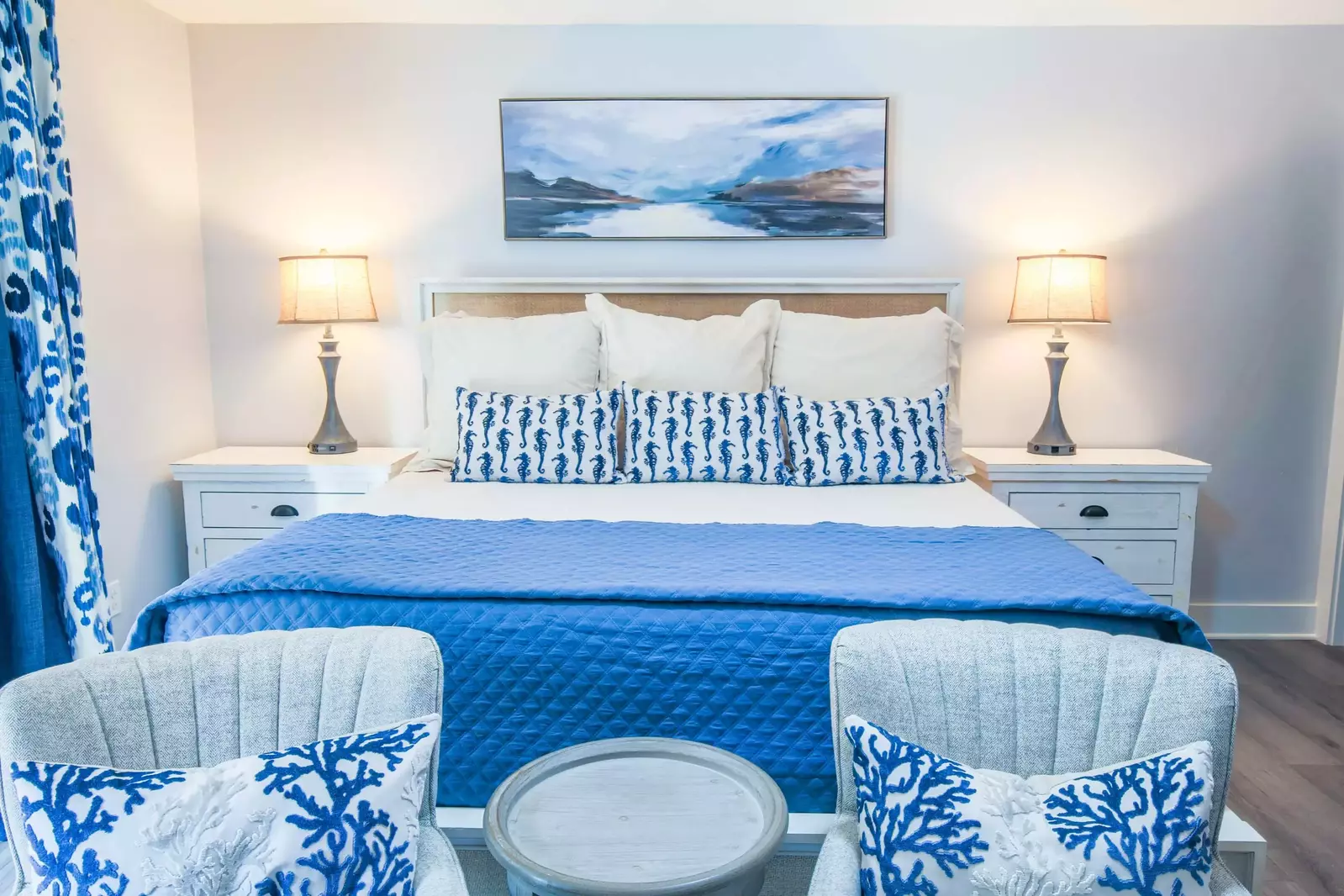 This master suite features a king bed, night stands with reading lamps and a seating area.