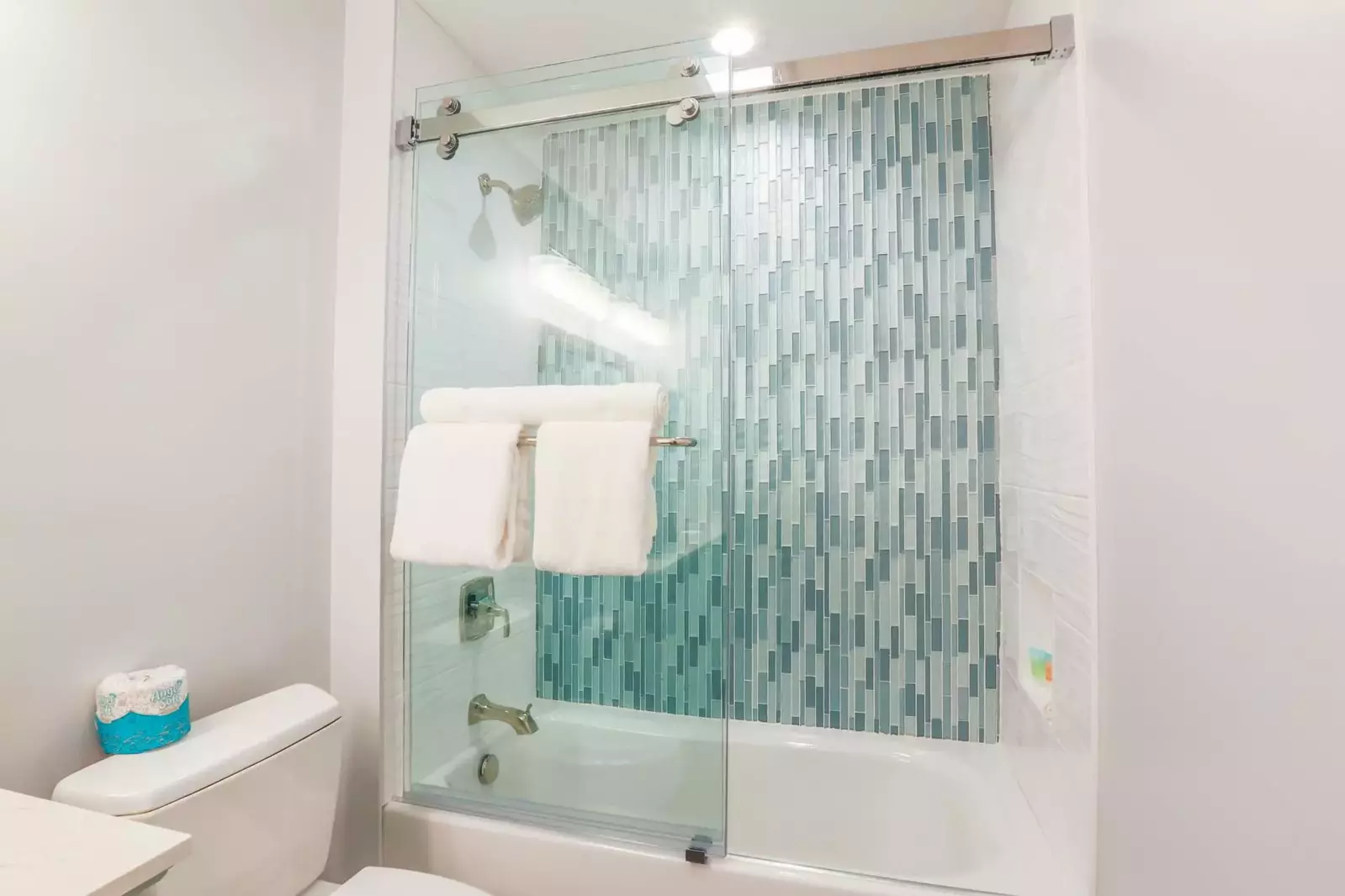 This hallway bathroom also has a tiled, shower/tub combo.