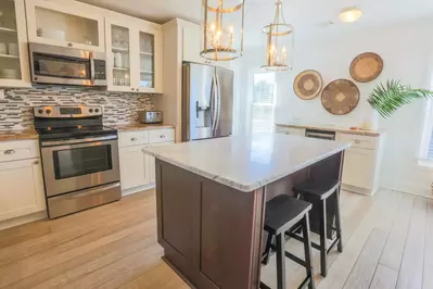 The kitchen features stainless steel appliances, a tiled backsplash, new floors and new cabinets.