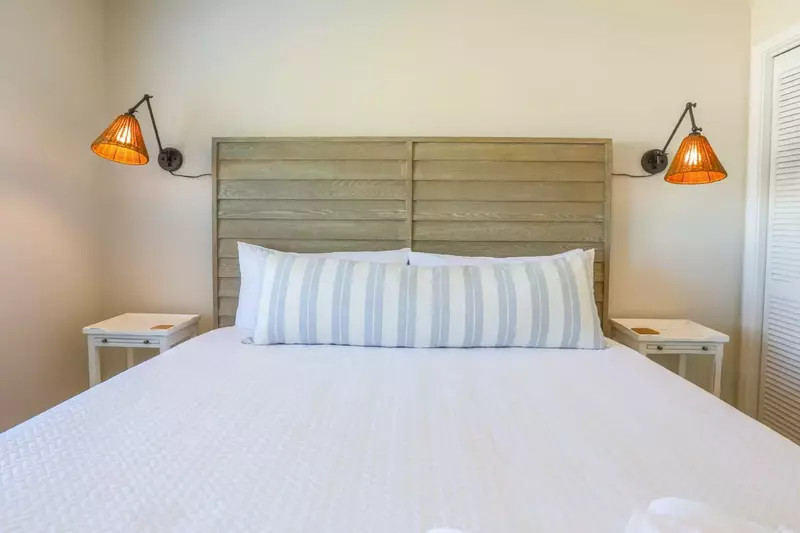 The third bedroom in the home features a king bed, nightstands and wall sconces.